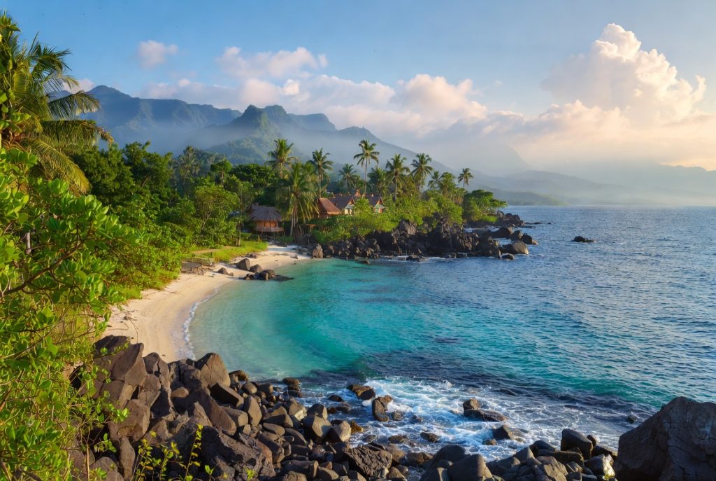 Wisatawan menikmati matahari terbenam di tepi Danau Toba, Pulau Samosir, dengan latar belakang perahu tradisional.